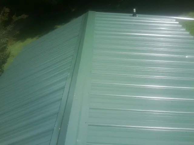 New green metal panels meeting at the ridge of a roof — Flat Roof Repair work by our crew in Scenery Hill