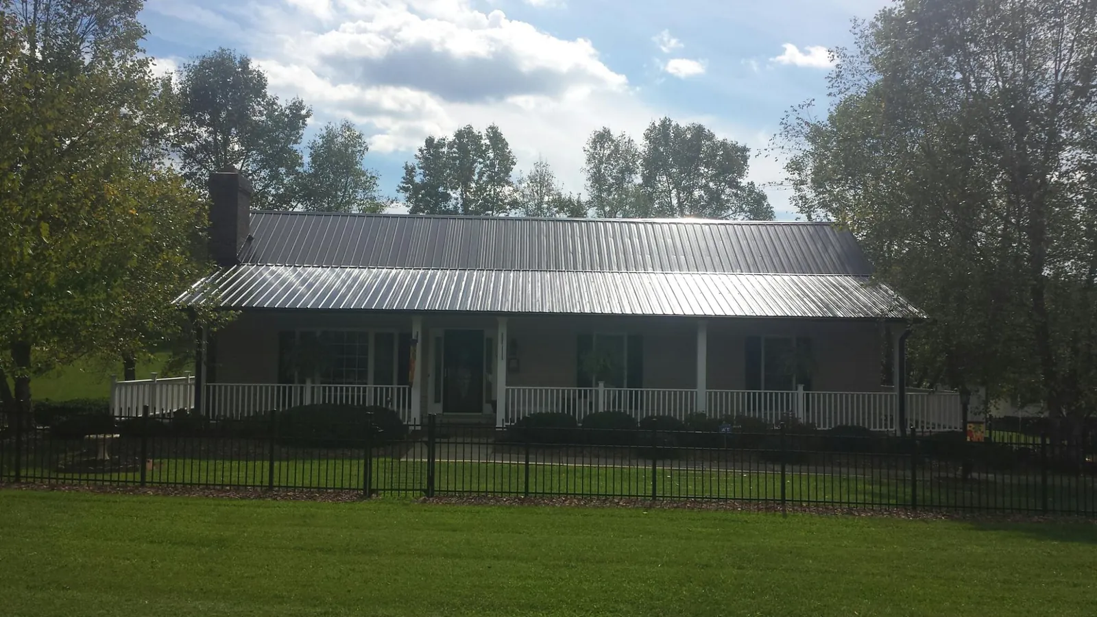 Gray metal roof on a brick ranch with a full width front porch — Gutter Guard Installation work by our crew in Scenery Hill