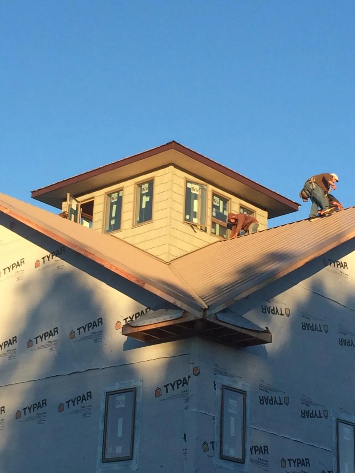 Roofers working around a rooftop cupola on a new metal roof at sunset — Roof Waterproofing in Scenery Hill by Roofing Brothers